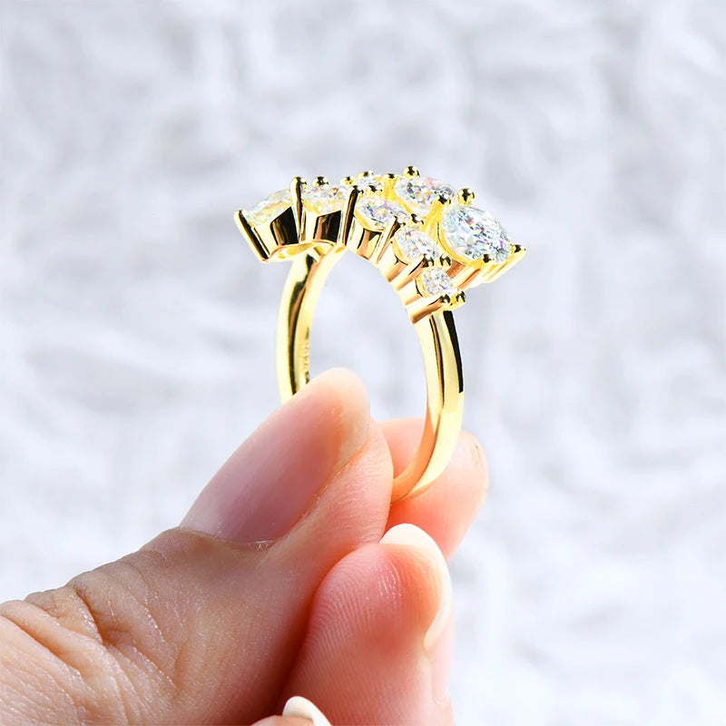 Bague de fiançailles dix pierres en argent 925 plaqué or jaune et diamants montrée entre les doigts d'une femme vue de côté.