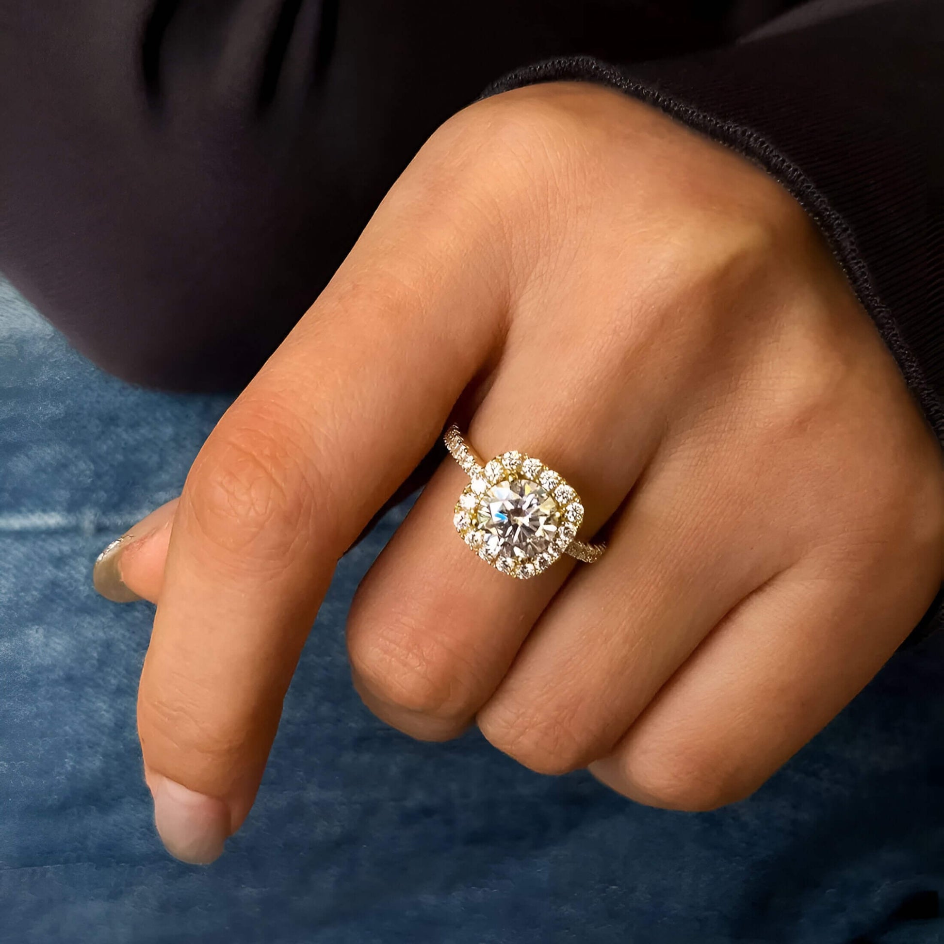 Bague de fiançailles en argent plaqué or jaune raffiné avec diamant central en moissanite et zircon naturels de forme ronde portée au doigt d'une femme vue de face.