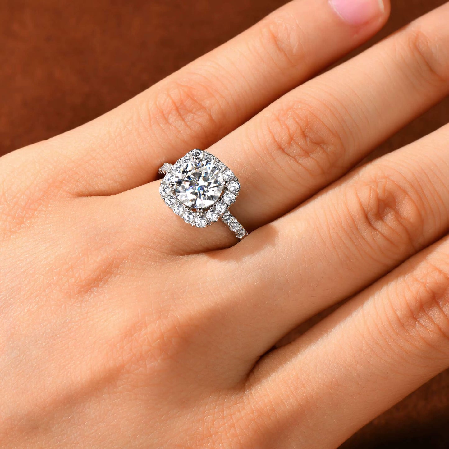 Bague de fiançailles halo de diamants en argent 925 plaqué or blanc portée au doigt d'une femme vue du dessus.