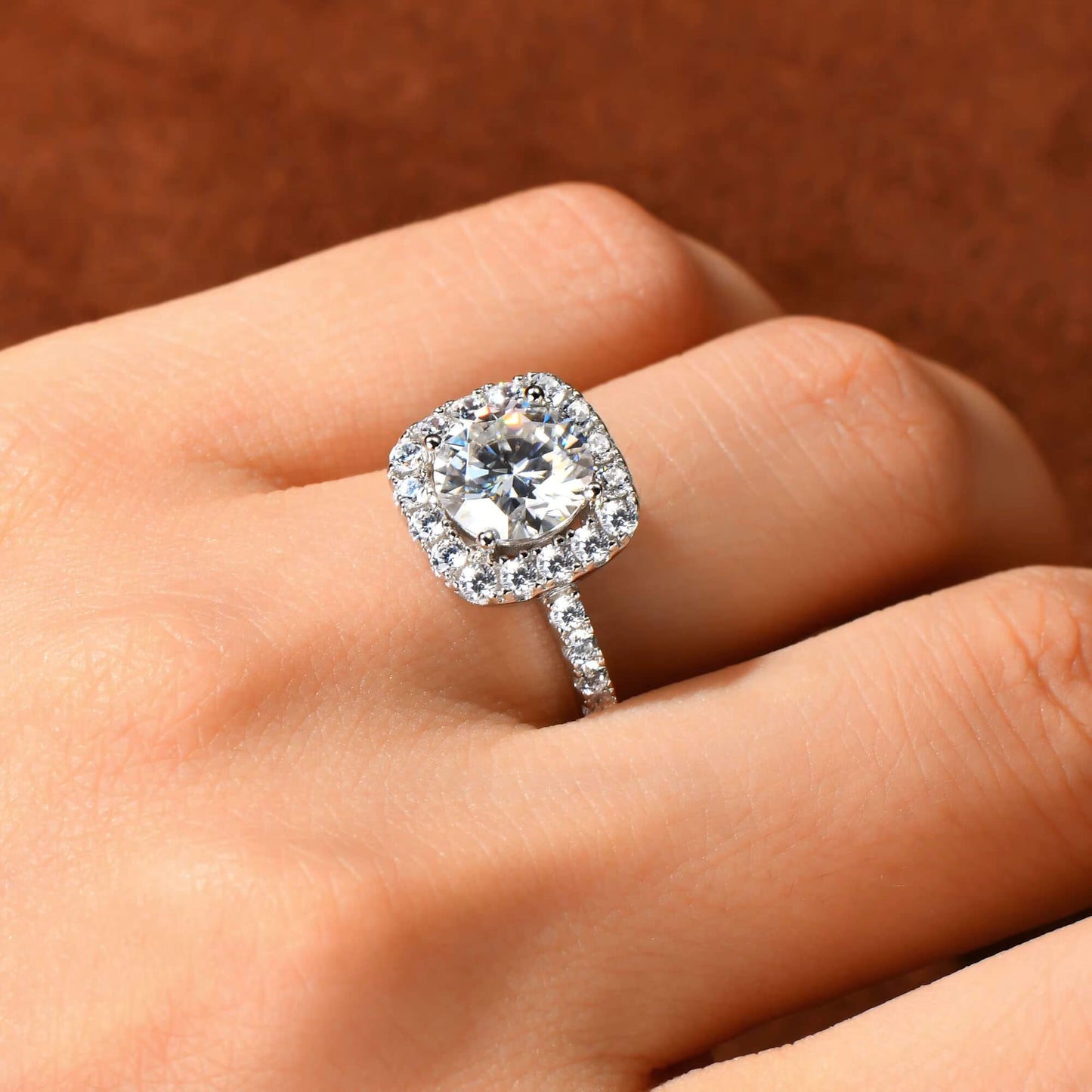 Bague de fiançailles halo de diamants scintillants en argent 925 plaqué or blanc portée au doigt d'une femme vue de proche.