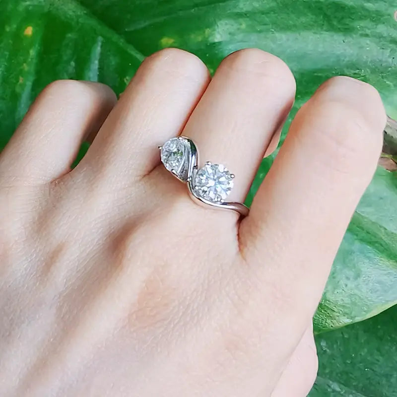 Bague de fiançailles en or blanc et diamant synthétique portée au doigt d'une femme.