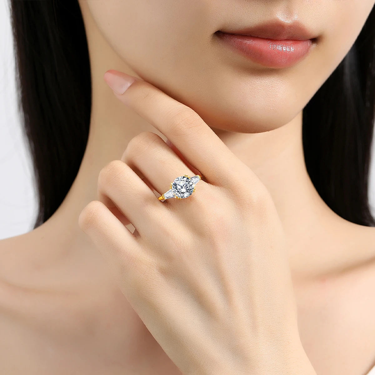 Variante 3CT de la bague de fiançailles triple diamants Moriah en or jaune 14K flamboyant portée au doigt d'une femme vue de proche.