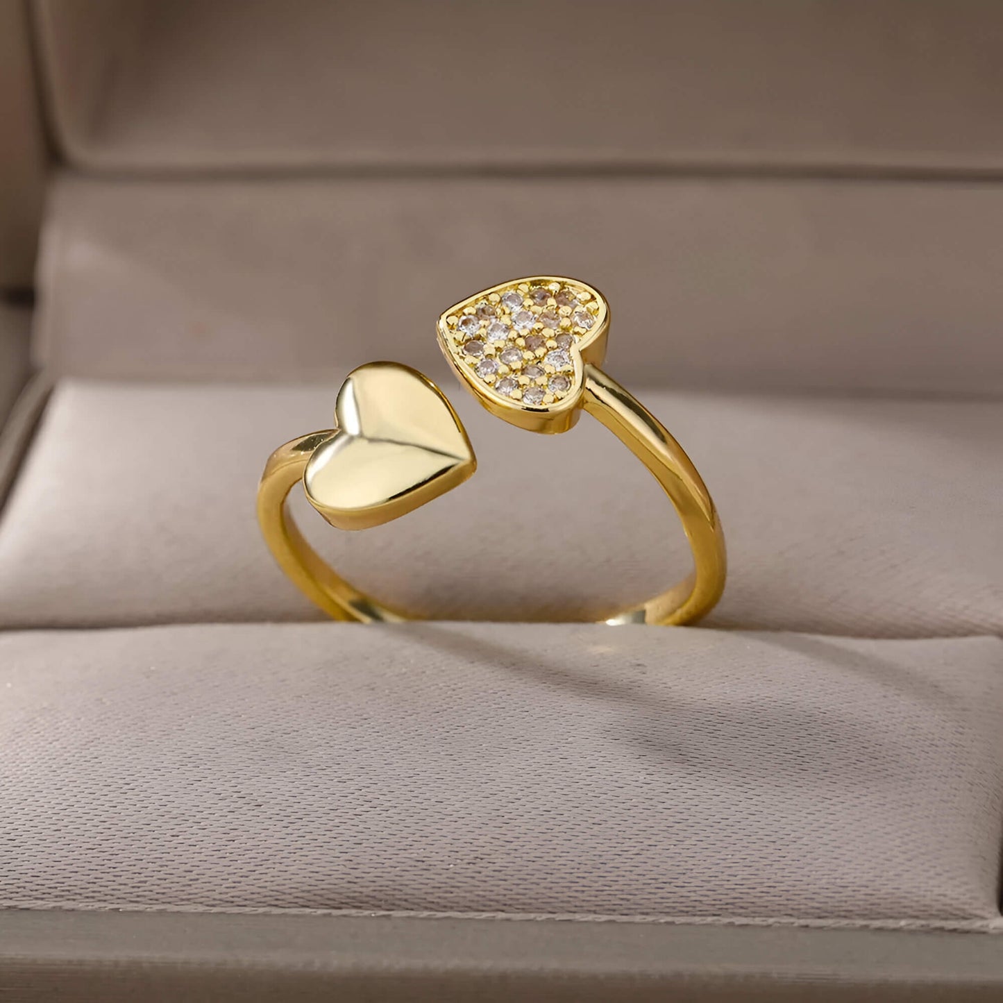 Bague double cœur doré Lumira en acier inoxydable plaqué or jaune 18K chaleureux et petits diamants ronds rangée dans son écrin.