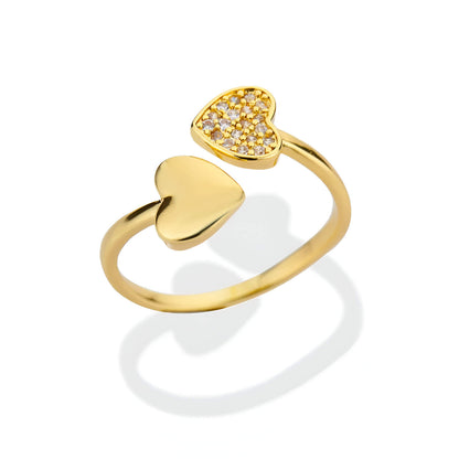 Bague double cœur doré Lumira en acier inoxydable plaqué or jaune 18K et petits diamants ronds sur fond blanc.