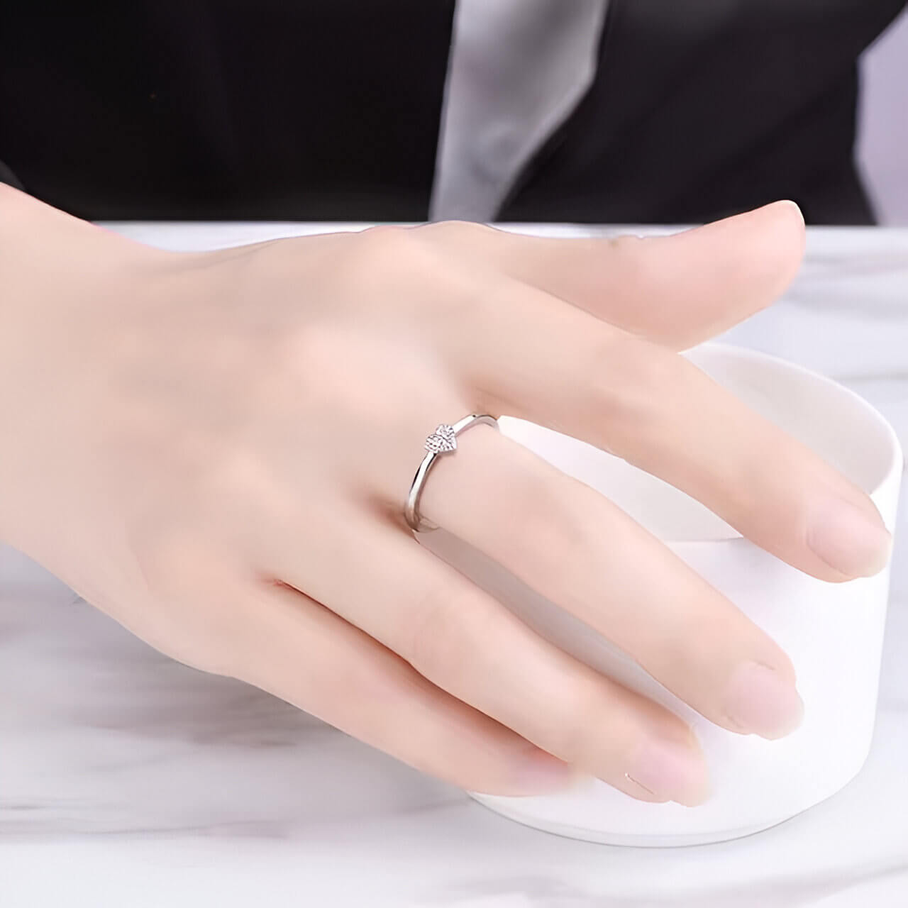 Bague fantaisie en or blanc et oxyde de zirconium portée au doigt d'une femme.