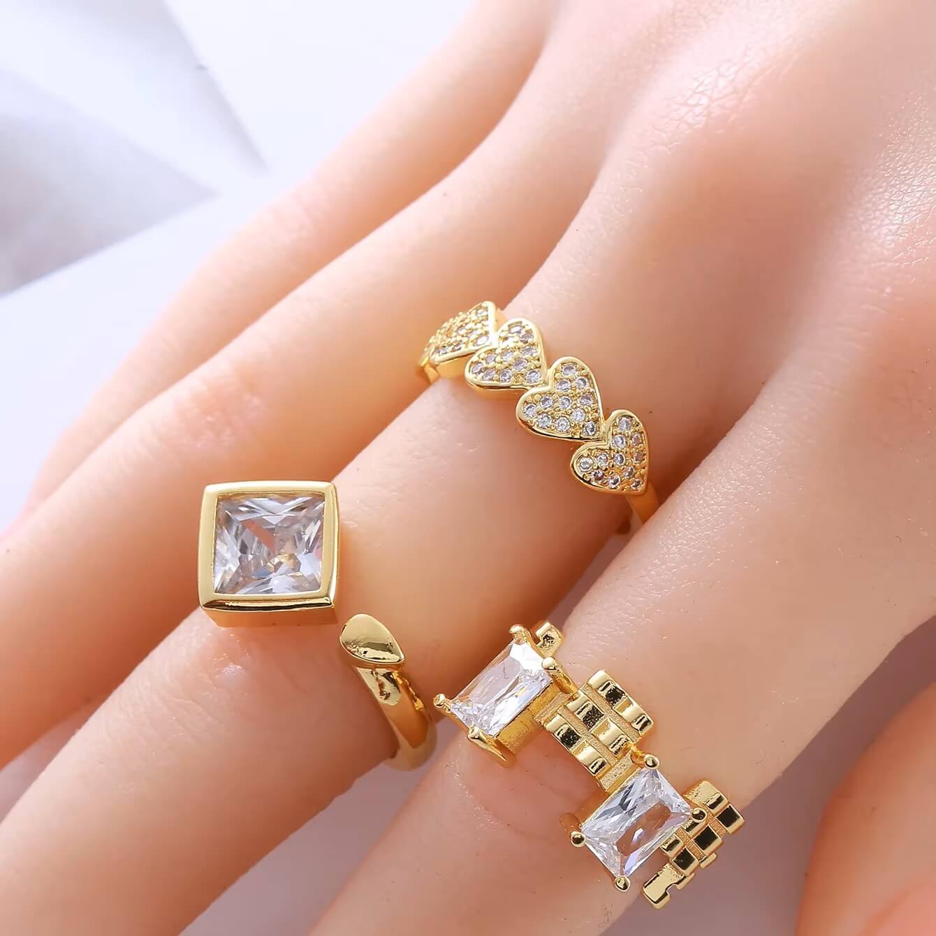 Bague fantaisie ouverte cœurs en acier et or jaune sertie de diamants naturels portée au doigt d'une femme.