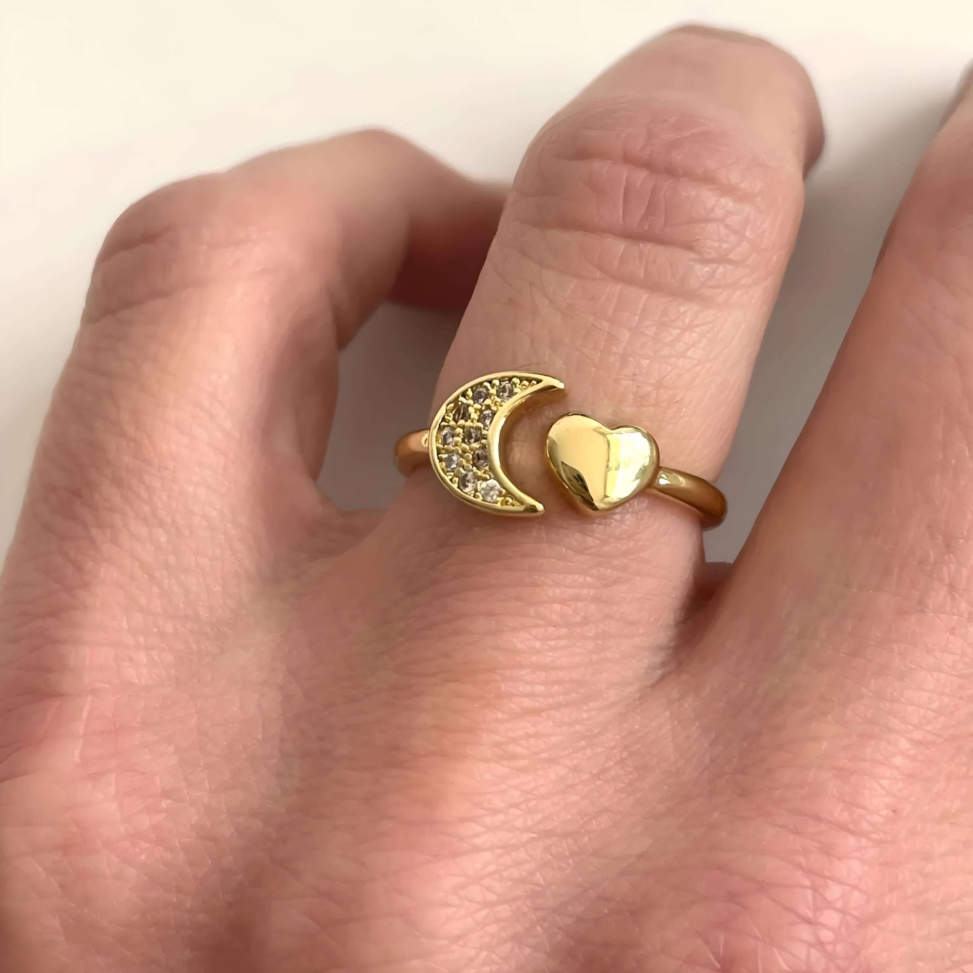 Bague fantaisie ouverte cœur et croissant de lune en acier inoxydable et or jaune sertie de diamants naturels portée au doigt d'une femme.