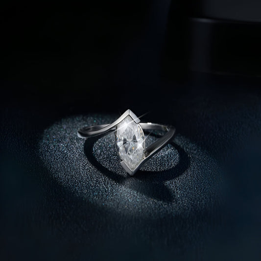 Bague moissanite marquise solitaire en argent à plat vue de face sur du granite noir.