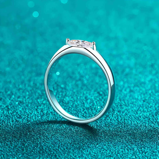 Bague solitaire dune de diamant vue latérale sur du granite bleu cyan.