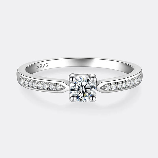 Bague solitaire emprise de moissanite à plat vue de face sur fond blanc cassé.