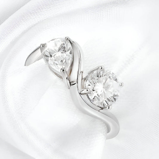 Bague ondulée paire de diamants portée par une nappe blanche vue du dessus.