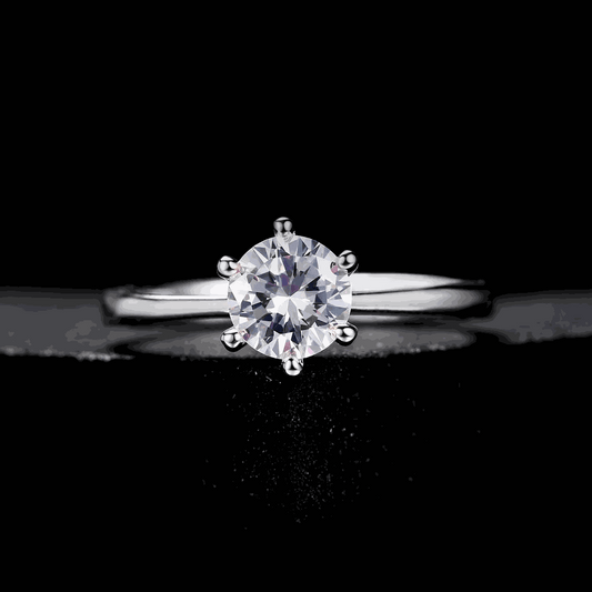 Bague solitaire six griffes en argent à plat vue de face sur fond noir.