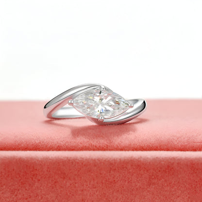 Bague diamant marquis solitaire à plat vue de face sur une surface rose bonbon.