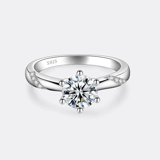 Bague solitaire six griffes sertie de diamants à plat vue de face sur fond blanc cassé.