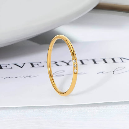 Variante 3 pierres de la bague fine 1mm Cassiane en acier inoxydable plaqué or jaune 18K et oxyde de zirconium vue de proche.