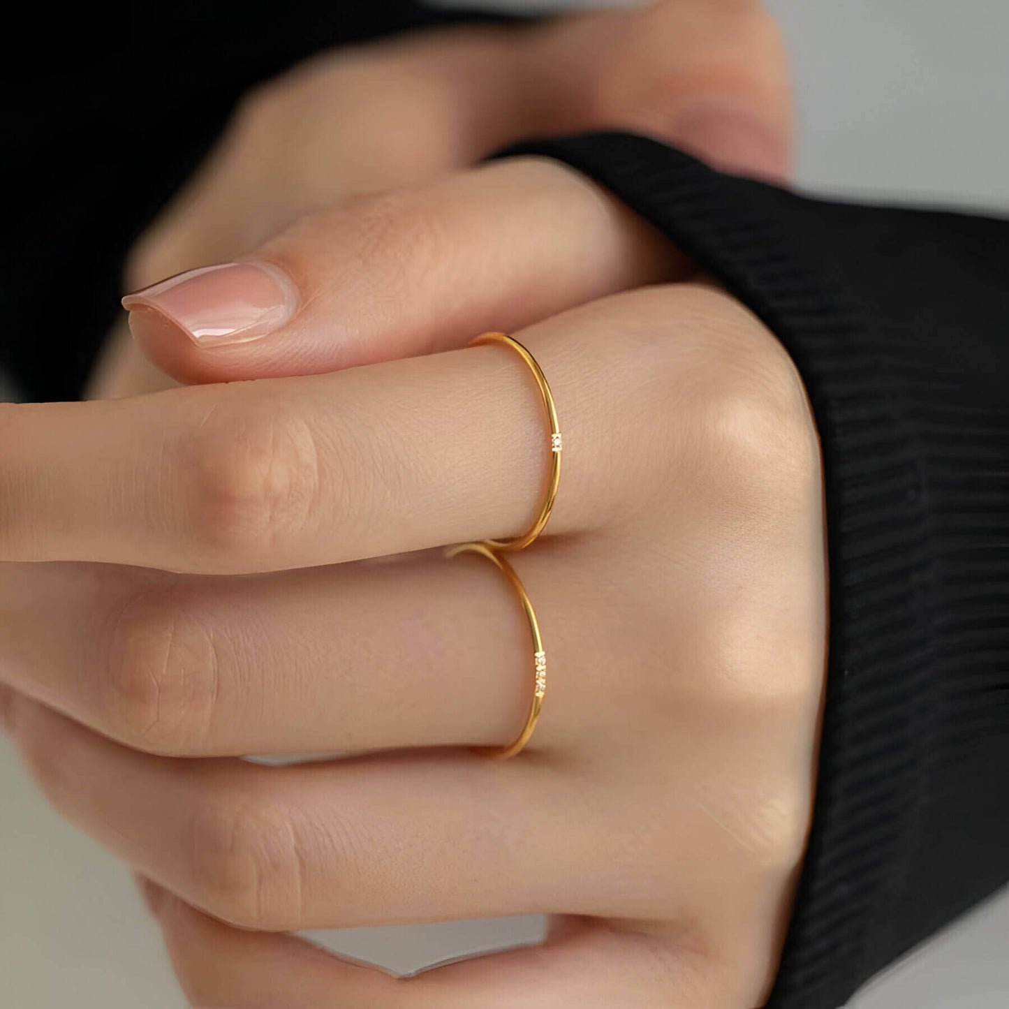 Variantes 1 pierre et 3 pierres de la bague fine 1mm Cassiane en acier plaqué or jaune 18K et oxyde de zirconium portées aux doigts d'une femme vue de face.