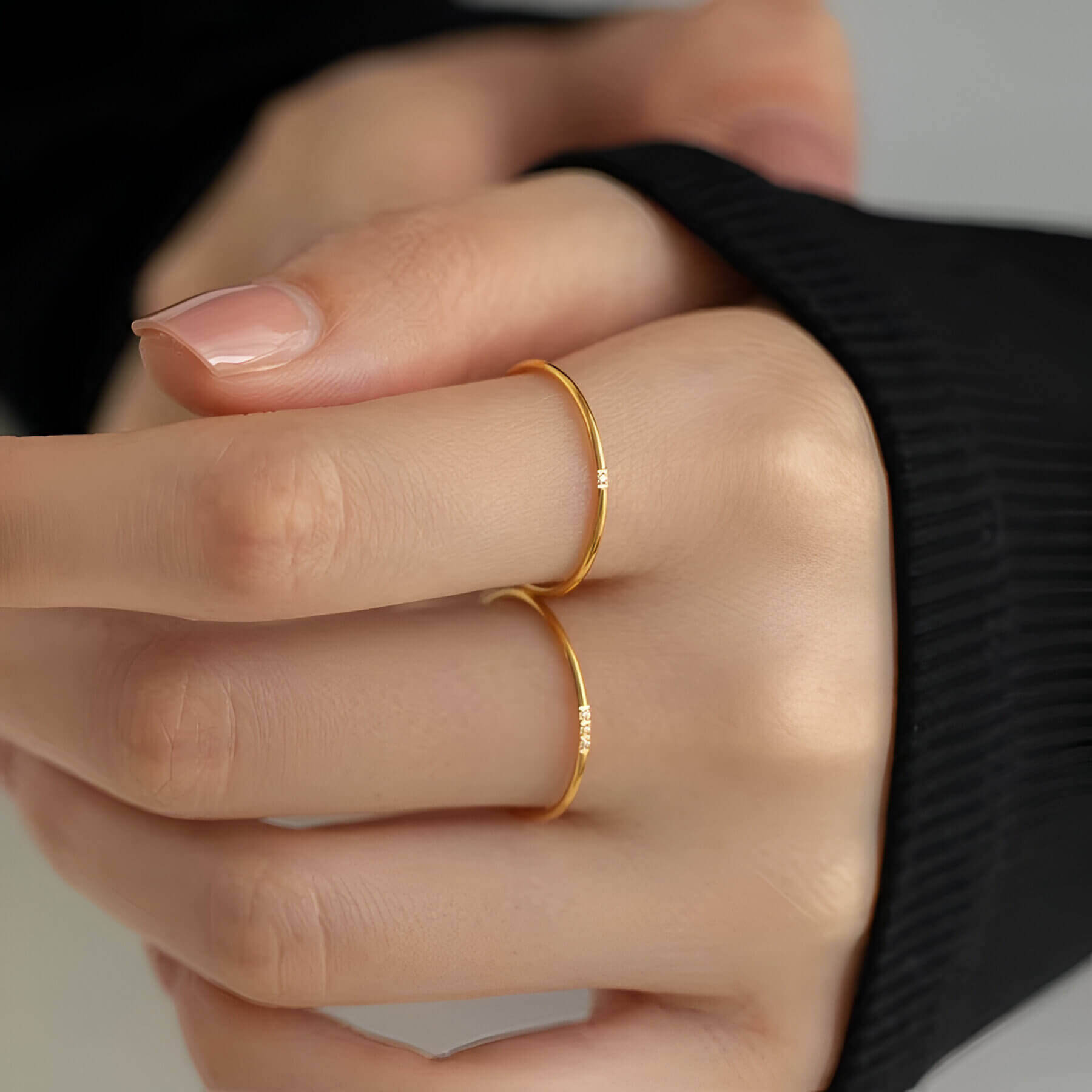 Variantes 1 pierre et 3 pierres de la bague fine 1mm Cassiane en acier plaqué or jaune 18K et oxyde de zirconium portées aux doigts d'une femme vue de face.