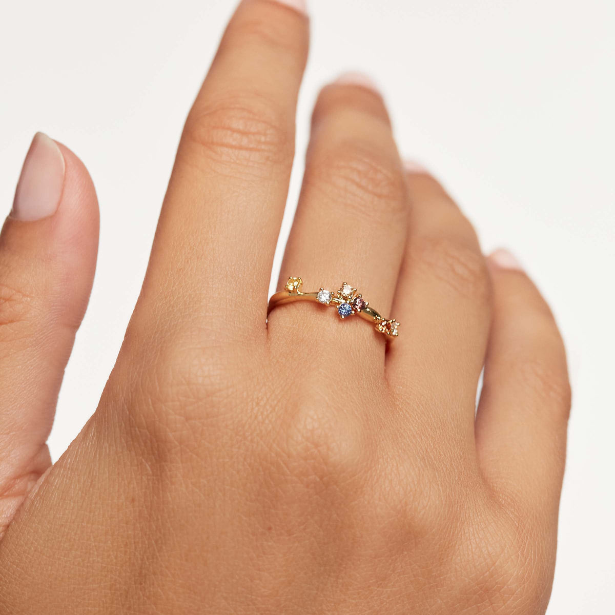 Bague fine diamants multicolores asymétrique Floria en argent 925 plaqué or jaune portée au doigt d'une femme vue de face.