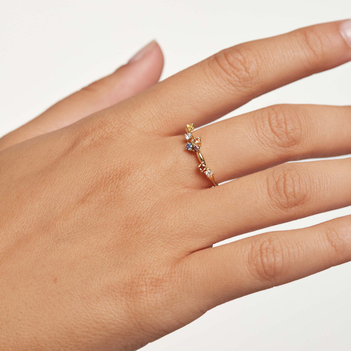 Bague fine diamants multicolores asymétriques scintillants Floria en argent 925 plaqué or jaune portée au doigt d'une femme vue de proche.