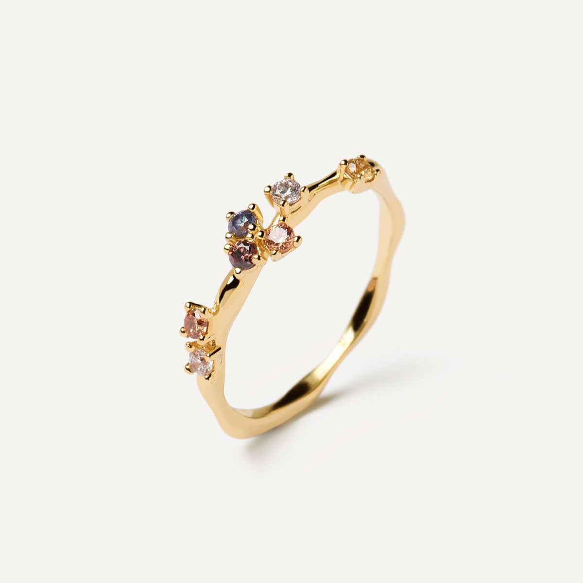 Bague fine diamants multicolores asymétrique Floria en argent 925 plaqué or jaune sur fond blanc cassé.