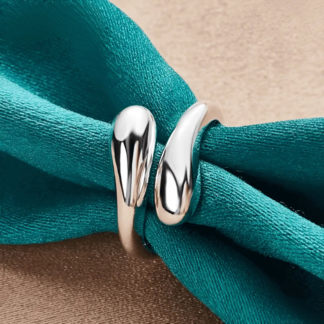 Bague goutte argentée en argent 925 plaqué or blanc portée par une nappe.