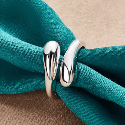 Bague goutte argentée en argent 925 plaqué or blanc portée par une nappe.