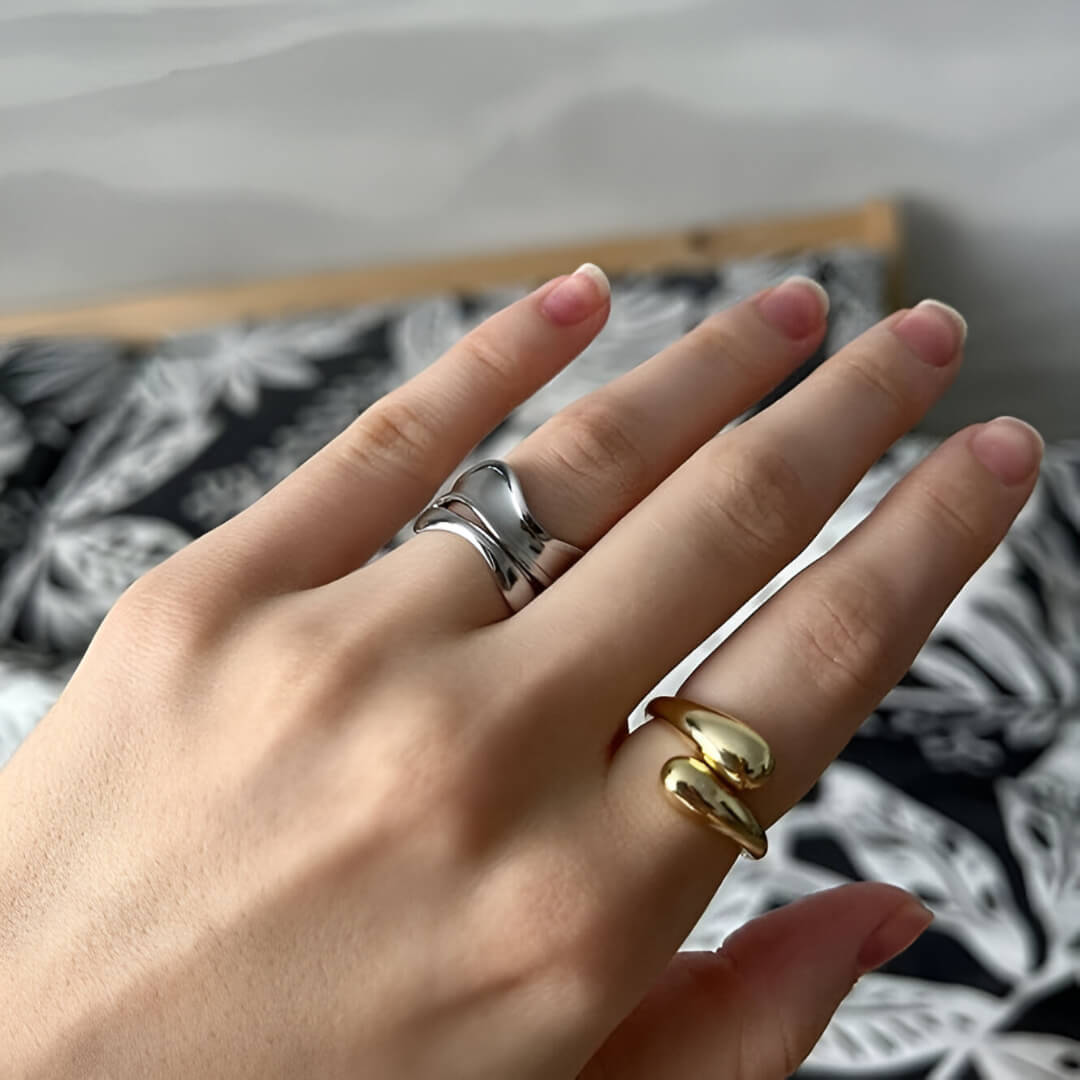 Bague goutte d'eau en acier inoxydable et or jaune portée au doigt d'une femme.