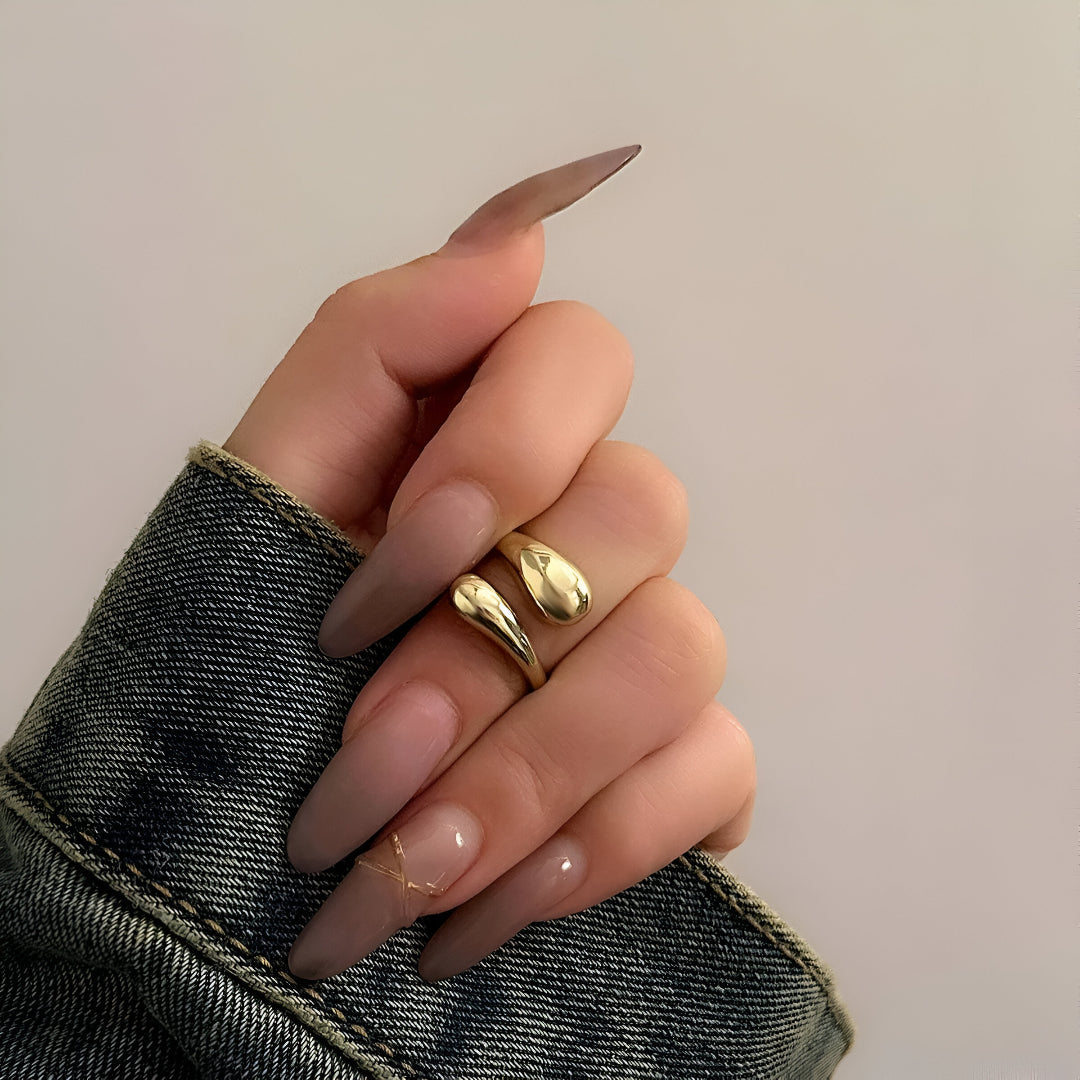 Bague goutte d'eau en acier inoxydable et or jaune portée au doigt d'une femme vue de face.