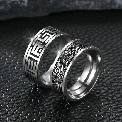 Bague gravée à bande en acier blanc variantes géométrique et fluide debout sur fond noir.