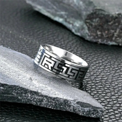 Bague gravée à bande en acier blanc variante géométrique posée sur une pierre.