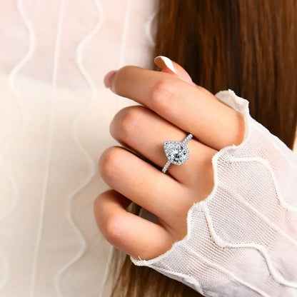 Bague diamant goutte 2CT Aelysë en argent sterling 925 plaqué or blanc 18K et halo de diamants portée au doigt d'une femme vue de face.