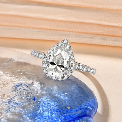 Bague diamant goutte 2CT Aelysë en argent 925 plaqué or blanc 18K et halo de diamants scintillants posée.