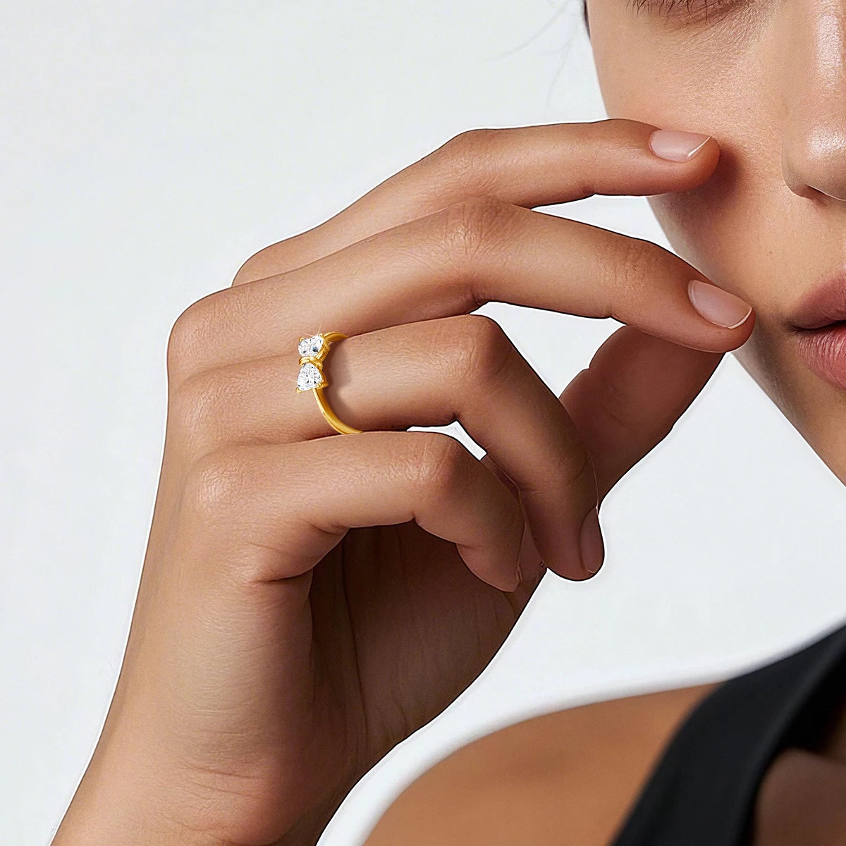 Bague nœud papillon Orélis en or jaune 14K et diamants cœurs brillants de 0.5CT portée au doigt d'une femme vue de loin.