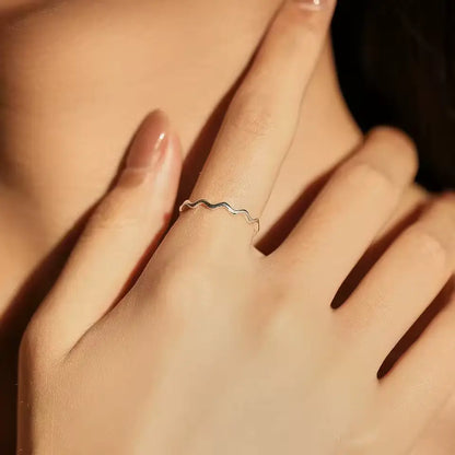 Bague ondulée en argent 925 rhodié portée au doigt d'une femme.