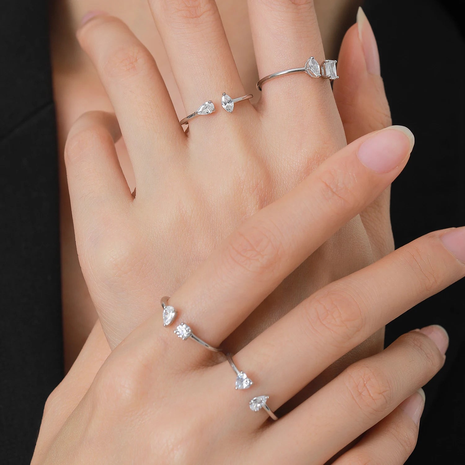 Doigt de femme portant la bague ouverte en argent sterling 925 éclats perpendiculaires, avec diamants en zircon et finition or blanc 18K. Accessoire chic et tendance