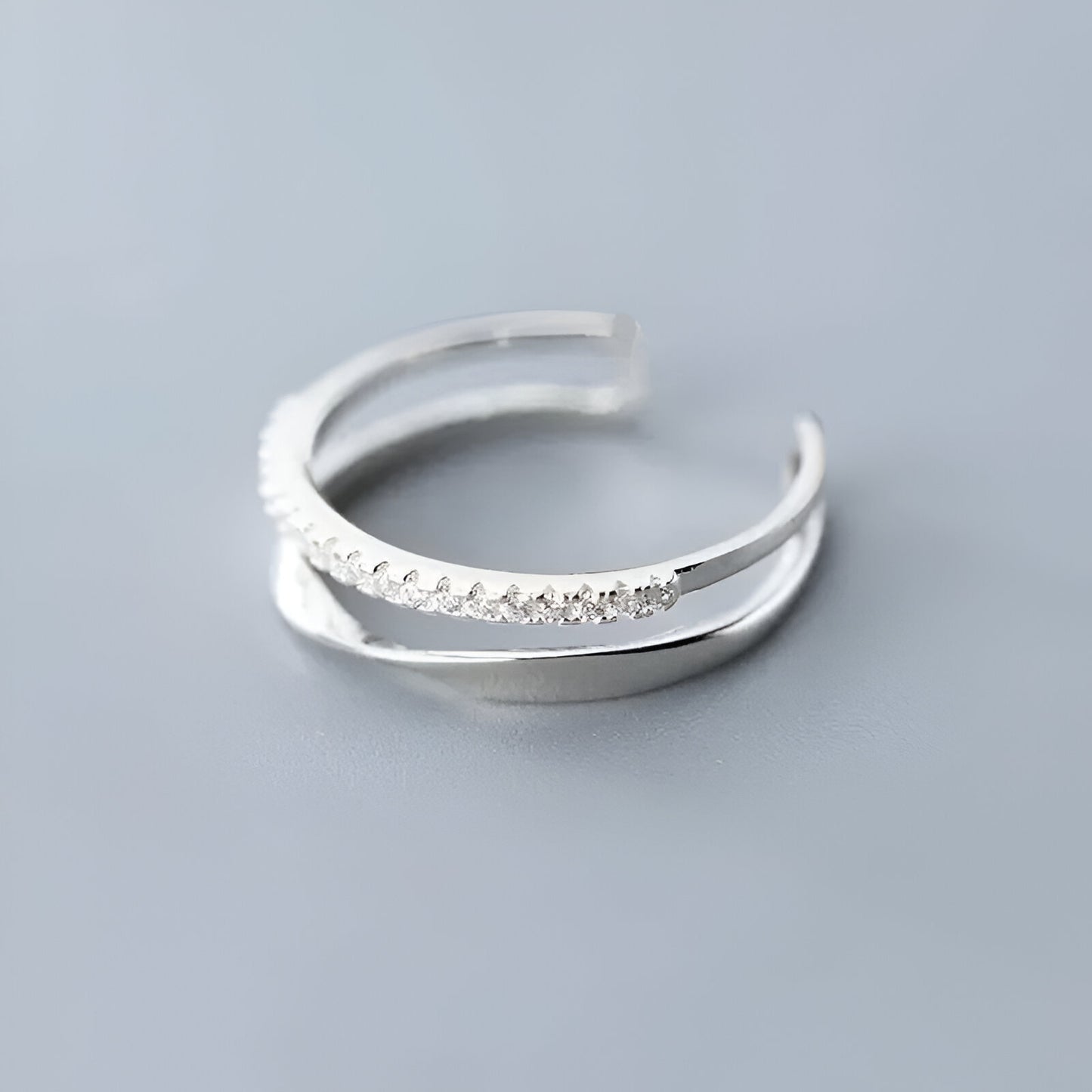 BAGUE OUVERTE EN ARGENT DEMI-MÖBIUS ÉCLATS DE ZIRCON - Vue rapprochée de la bague à plat, illustrant parfaitement les éclats de zircons scintillants sur le fil d’argent 925 pour une touche de luxe discrète - La Petite Rebelle.