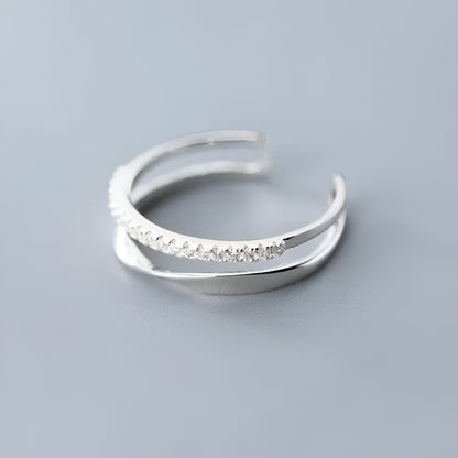 BAGUE OUVERTE EN ARGENT DEMI-MÖBIUS ÉCLATS DE ZIRCON - Vue rapprochée de la bague à plat, illustrant parfaitement les éclats de zircons scintillants sur le fil d’argent 925 pour une touche de luxe discrète - La Petite Rebelle.