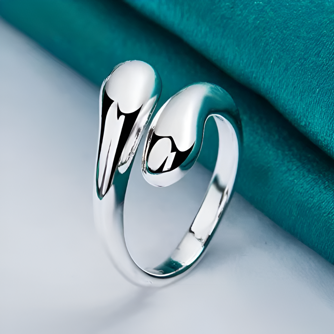 Bague ouverte en argent goutte d'eau posée sur une nappe bleue cyan, un design minimaliste et raffiné, parfait pour sublimer vos tenues avec une touche d'élégance. Matériau durable avec plaquage or blanc 14K - La Petite Rebelle