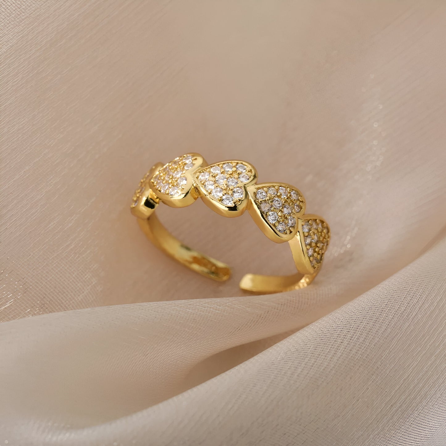 Vue du dessus de la bague ouverte en or dans un pli de tissu, design en cœur brillant et plaquage or 18K
