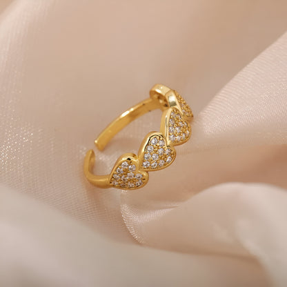 Bague ouverte en or scintillante sur tissu beige, ornée de cœurs en zircon pour un look romantique et luxueux
