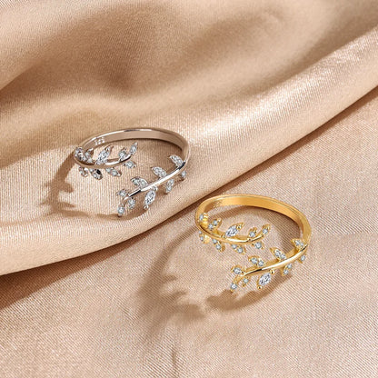 Variantes de la Bague ouverte feuille de laurier Caméllia en argent 925 plaqué or blanc ou plaqué or jaune et diamants scintillants à plat sur un drap vue de face.