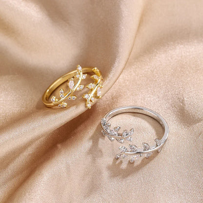Variantes de la bague ouverte feuille de laurier Caméllia en argent 925 plaqué or jaune ou plaqué or blanc et diamants posées sur un drap.