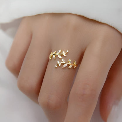 Bague ouverte feuille de laurier Caméllia en argent sterling 925 plaqué or jaune et diamants portée au doigt d'une femme vue de proche.