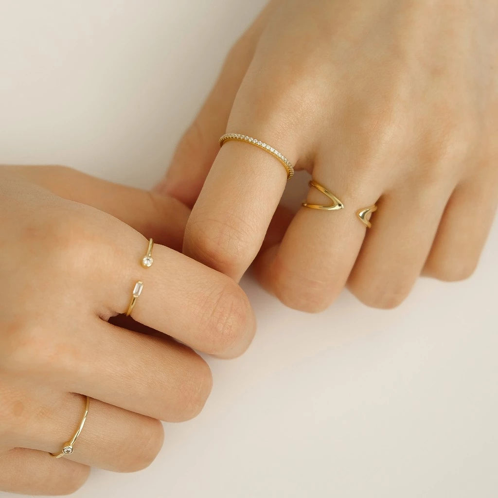 Bague ouverte fine de fiançailles Petrallis en argent 925 plaqué or jaune et diamants scintillants portée au doigt d'une femme vue de côté.