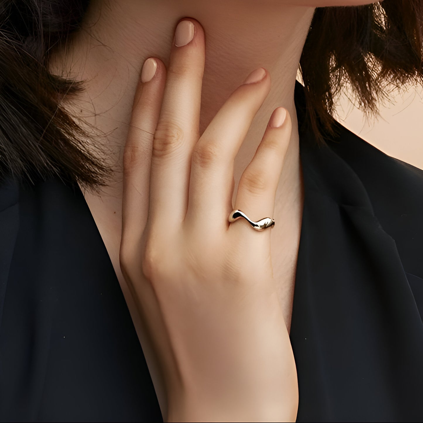 Bague ouverte ondulée en or blanc portée au doigt d'une femme.