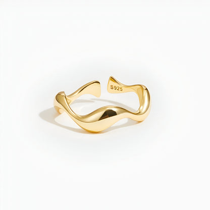 Bague ouverte ondulée en or jaune sur fond blanc.