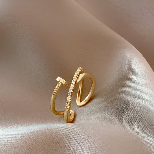 Bague ouverte clou torsadé variante or jaune debout sur une nappe.