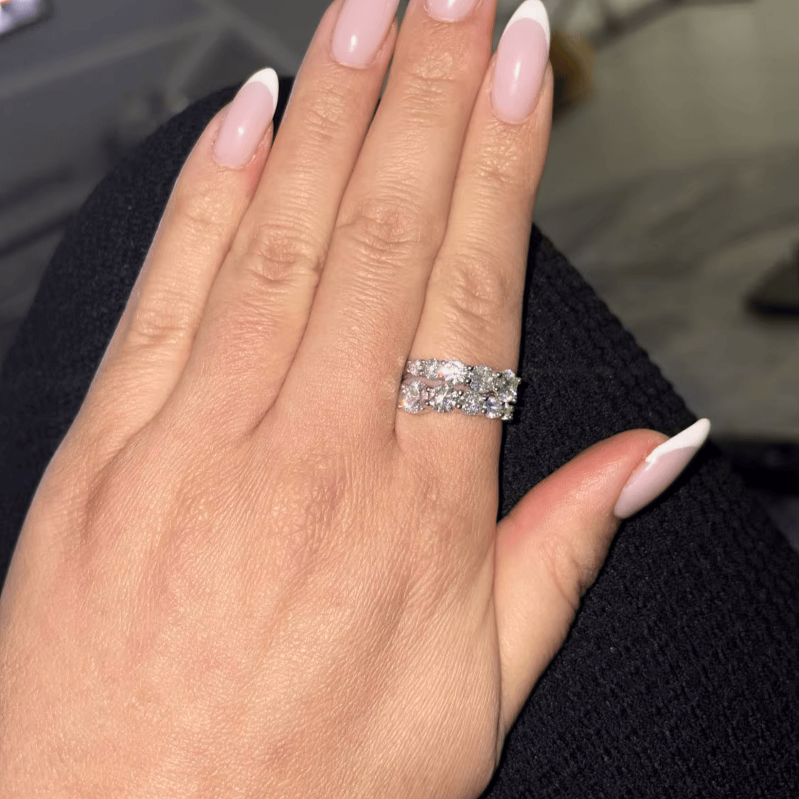 Bague ouverte en or blanc et diamants synthétiques portée au doigt d'une femme.