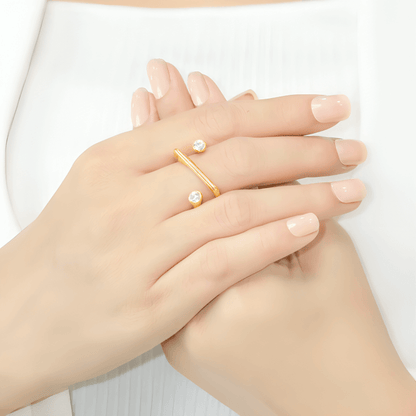 Bague fantaisie ouverte semi-tourbillon en acier inoxydable et or jaune sertie de cristaux portée au doigt d'une femme.