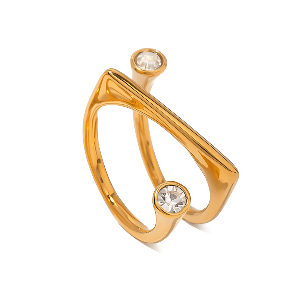 Bague fantaisie ouverte semi-tourbillon en acier inoxydable et or jaune sertie de cristaux sur fond blanc.